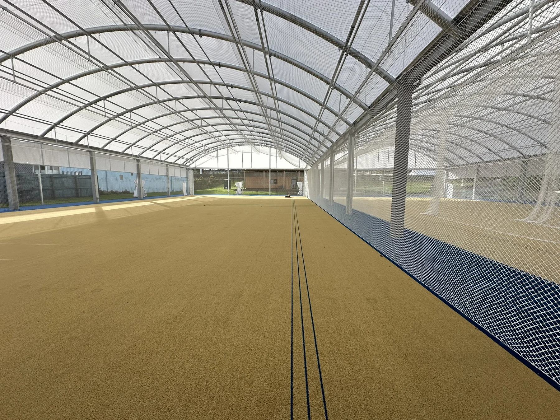 Inside Cricket Shield at Bradford Park Avenue, showing covered practice lanes, translucent roof, steel framing and retractable netting