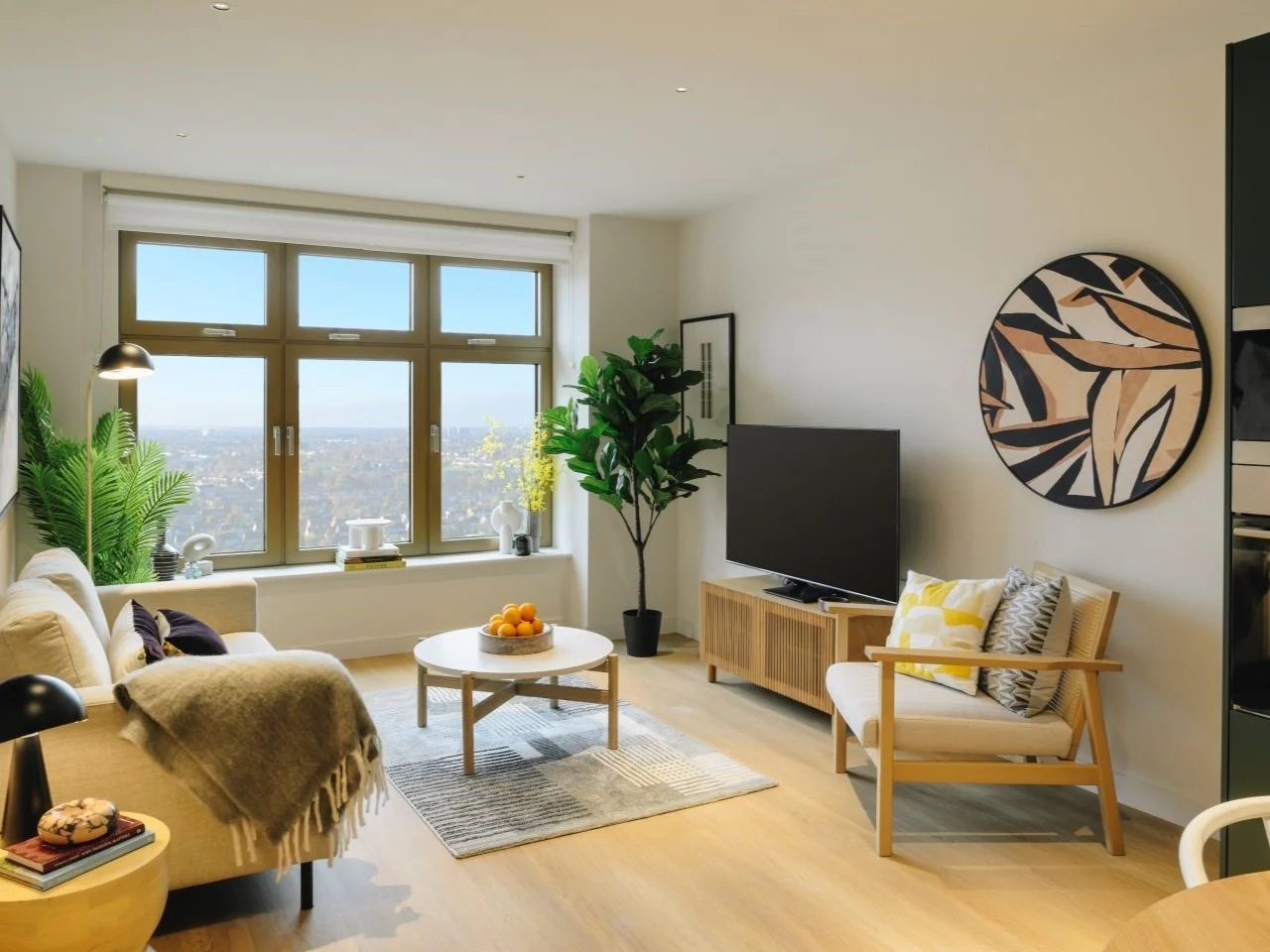A bright living room at The Wiltern, with broad windows, plants and pale timber furniture.