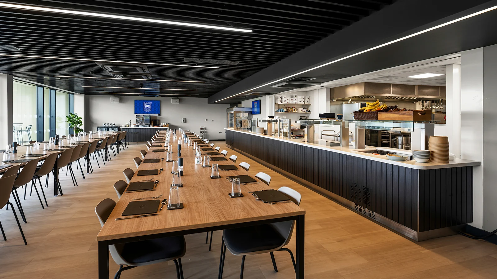 The dining room and open kitchen at the training complex, with long tables and integrated ceiling services.