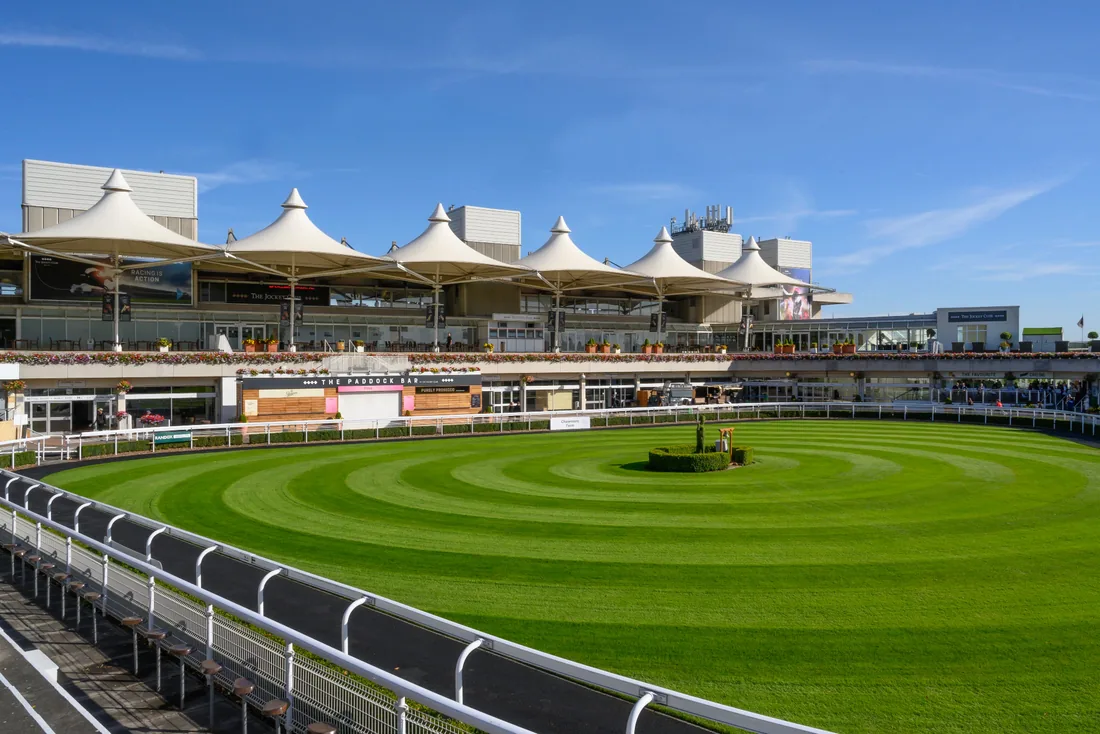 Racecourse grandstand with white canopy roofs overlooking a green paddock