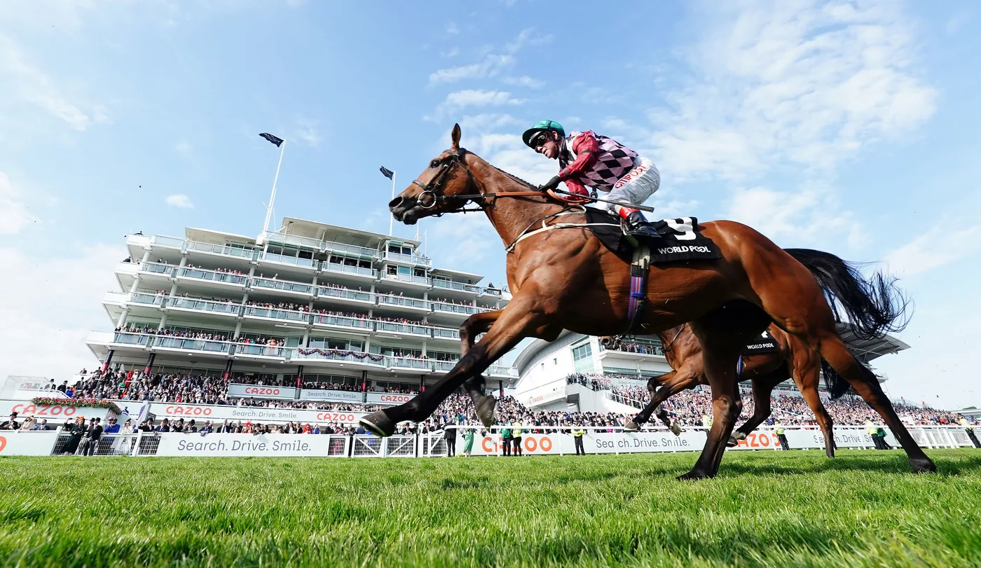 Racehorses and jockeys passing a spectator-filled grandstand