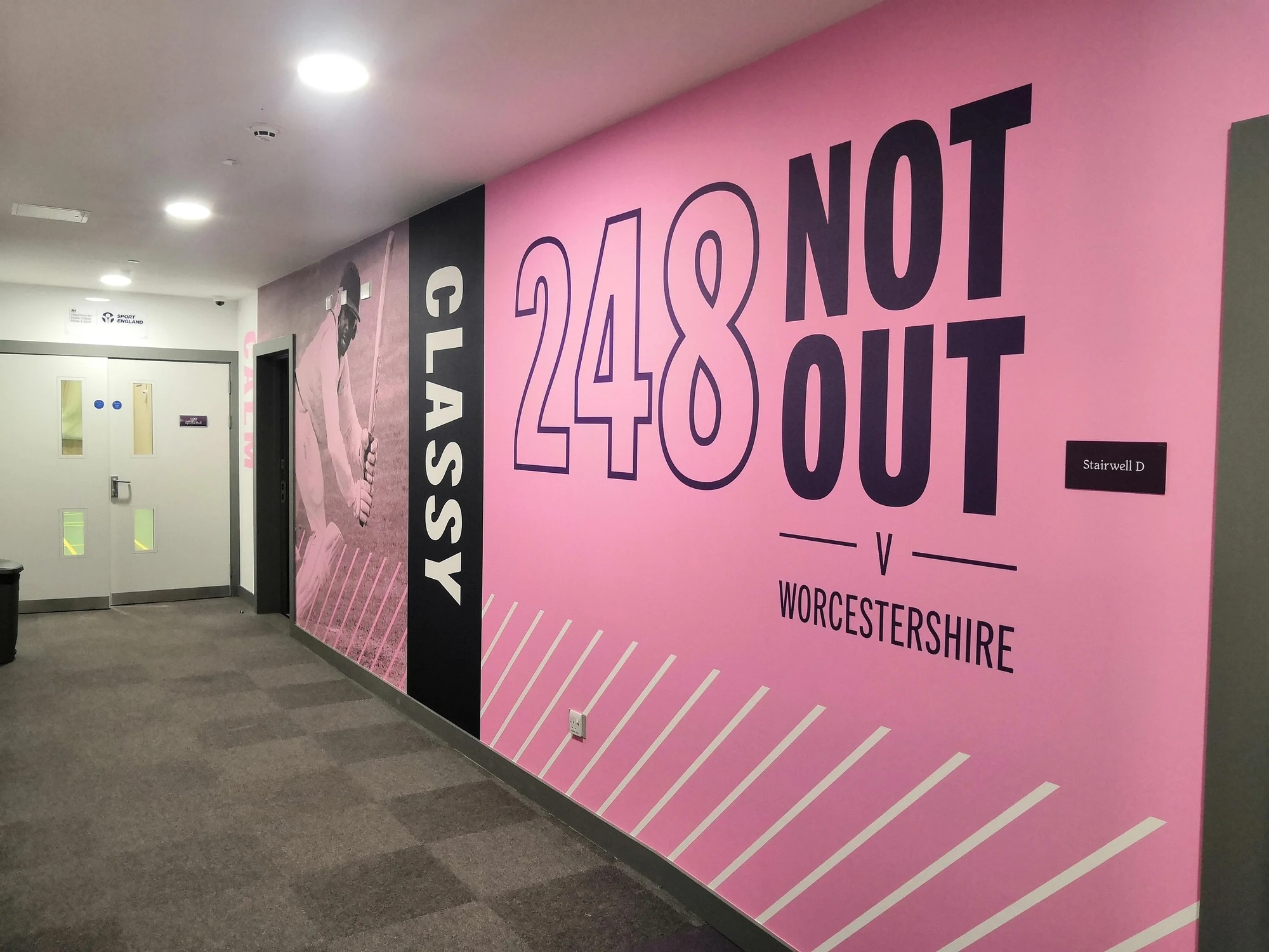 Wilf Slack Cricket Centre corridor with pink cricket-themed wall graphics